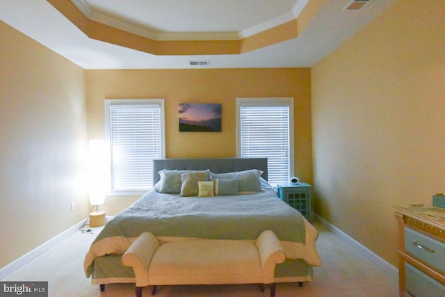 carpeted bedroom with crown molding and a tray ceiling