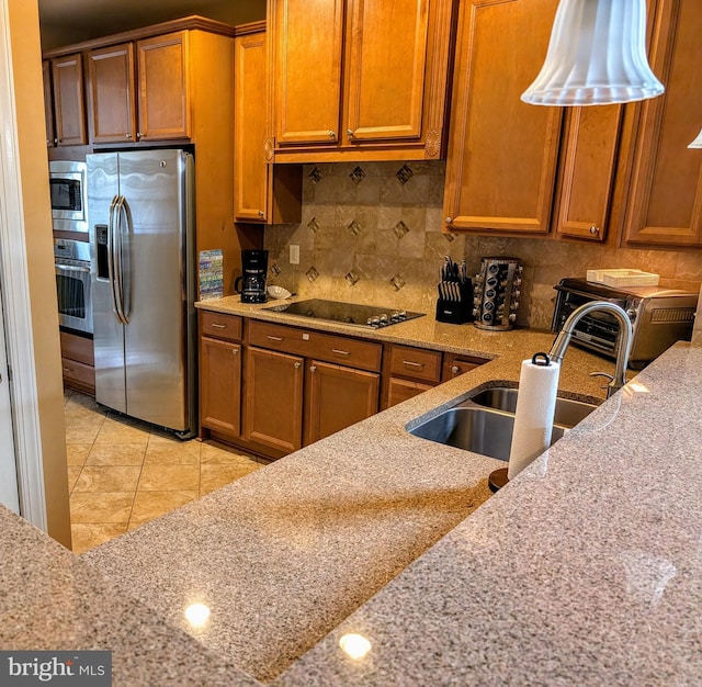 kitchen with stainless steel appliances, decorative backsplash, sink, light stone counters, and light tile patterned floors