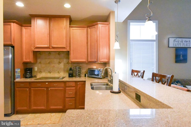 kitchen with pendant lighting, decorative backsplash, sink, stainless steel refrigerator, and a breakfast bar area