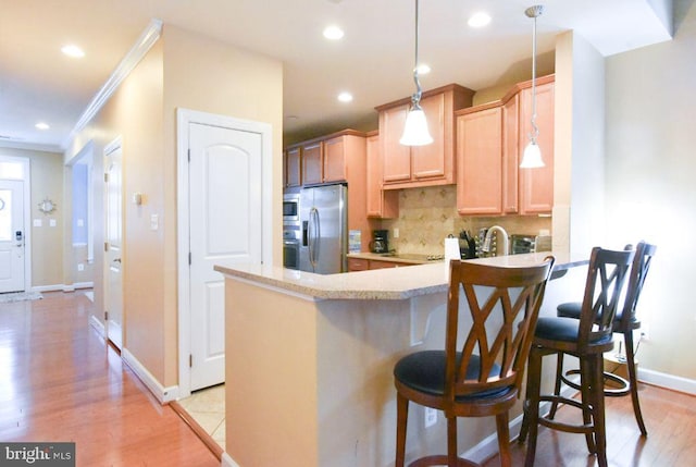 kitchen featuring stainless steel fridge with ice dispenser, a kitchen bar, kitchen peninsula, decorative light fixtures, and light brown cabinetry