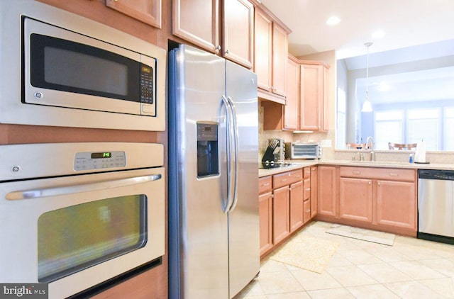 kitchen with light tile patterned floors, appliances with stainless steel finishes, sink, and pendant lighting