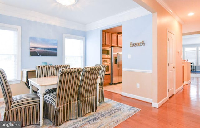 dining room featuring light wood-type flooring and crown molding