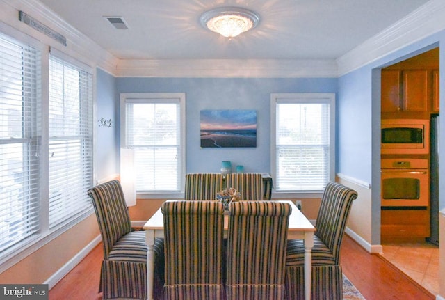 dining space with crown molding and light hardwood / wood-style flooring