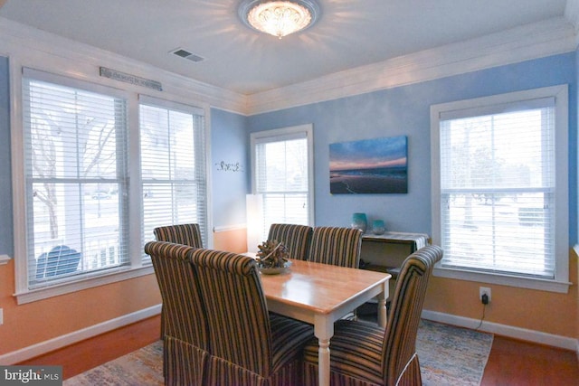 dining room featuring a healthy amount of sunlight, ornamental molding, and hardwood / wood-style floors