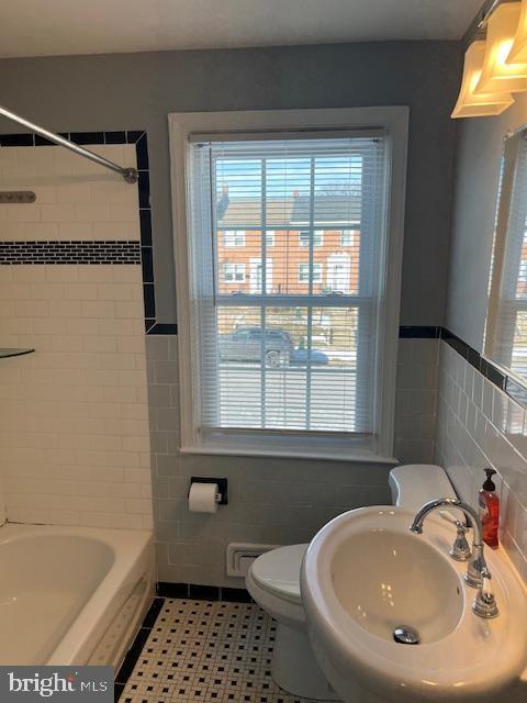 full bathroom featuring sink, toilet, tile patterned flooring, and tile walls