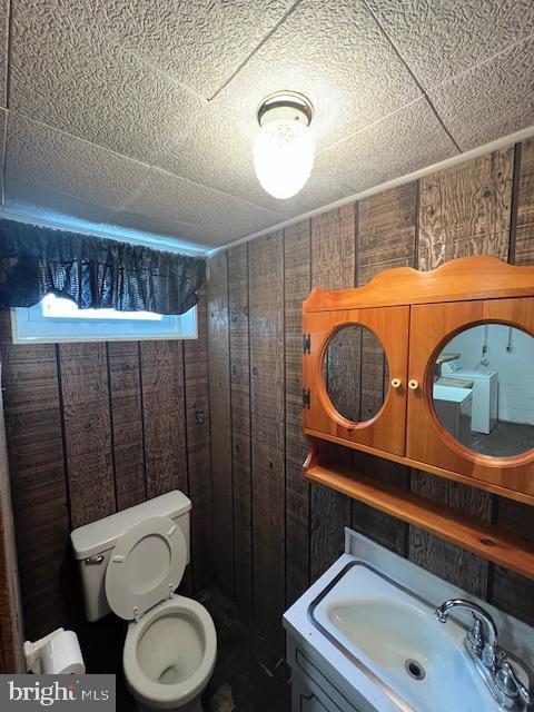 bathroom with sink, toilet, and wooden walls