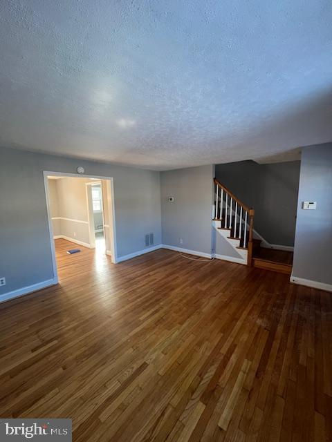 unfurnished living room featuring dark hardwood / wood-style floors and a textured ceiling