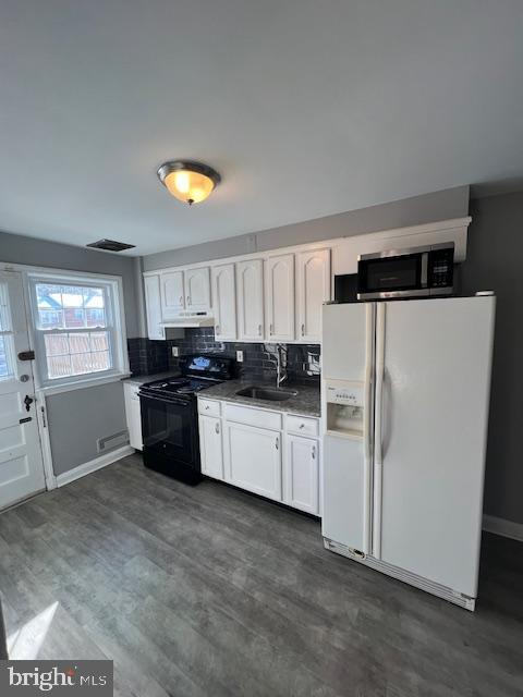 kitchen featuring sink, white fridge with ice dispenser, electric range, and white cabinetry