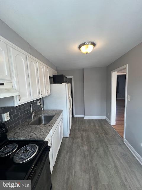 kitchen with sink, black range with electric stovetop, white cabinetry, and light stone counters