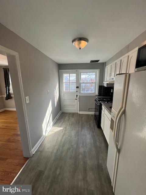 kitchen with white cabinetry, white fridge with ice dispenser, black electric range oven, and dark hardwood / wood-style flooring