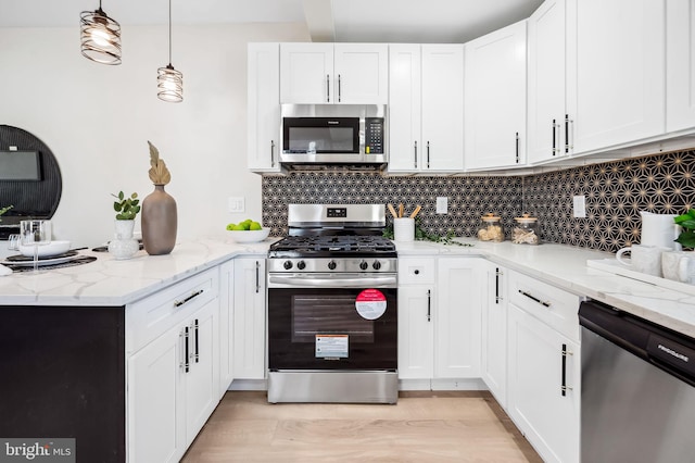 kitchen featuring decorative light fixtures, white cabinets, decorative backsplash, stainless steel appliances, and light stone countertops