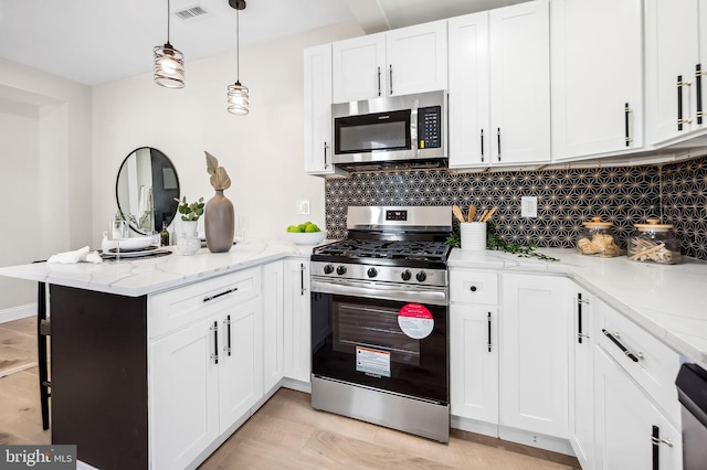 kitchen with light stone counters, kitchen peninsula, white cabinets, stainless steel appliances, and backsplash