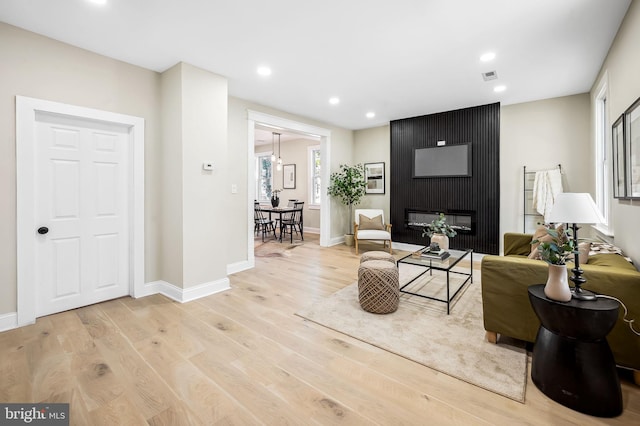 living room featuring light hardwood / wood-style floors and a large fireplace