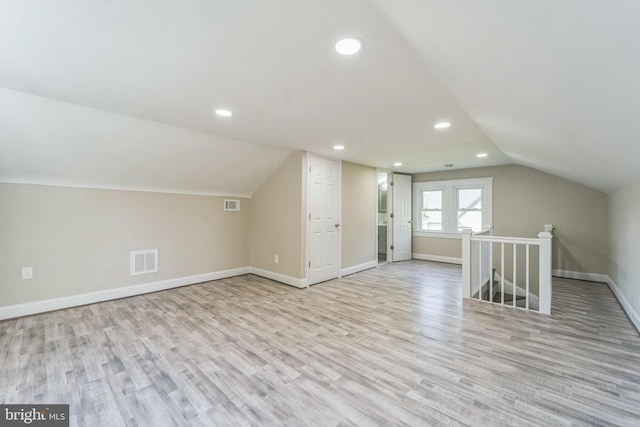 additional living space with light hardwood / wood-style floors and lofted ceiling