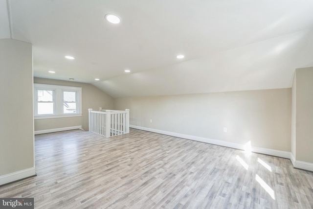 additional living space with light hardwood / wood-style floors and vaulted ceiling