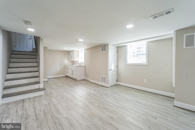 basement with light hardwood / wood-style floors and sink