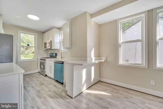 kitchen featuring white cabinets, backsplash, stainless steel appliances, and a healthy amount of sunlight