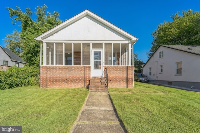 view of front of property featuring a sunroom and a front lawn