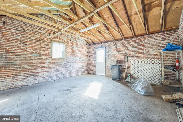 misc room with high vaulted ceiling and brick wall