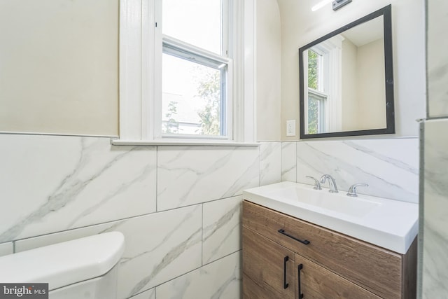 bathroom featuring vanity, toilet, and tile walls