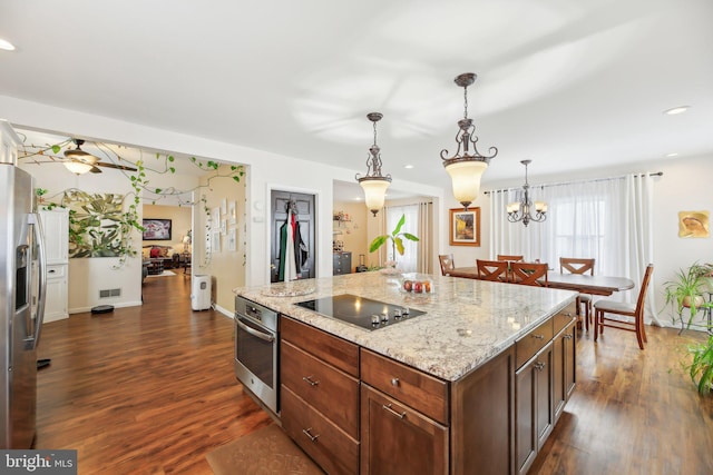 kitchen featuring light stone countertops, stainless steel appliances, pendant lighting, dark hardwood / wood-style floors, and a kitchen island