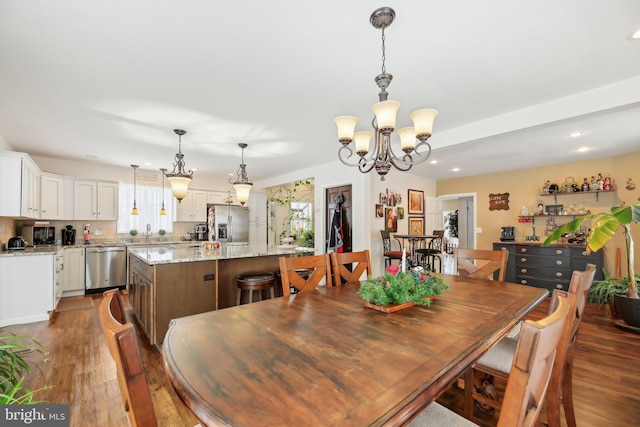 dining area with dark wood-type flooring, a chandelier, and sink