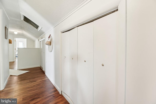 hallway featuring a textured ceiling, dark hardwood / wood-style flooring, and lofted ceiling