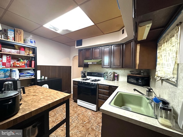 kitchen with a paneled ceiling, dark brown cabinetry, sink, and white range with gas cooktop