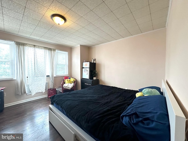 bedroom featuring dark hardwood / wood-style flooring, ornamental molding, and multiple windows