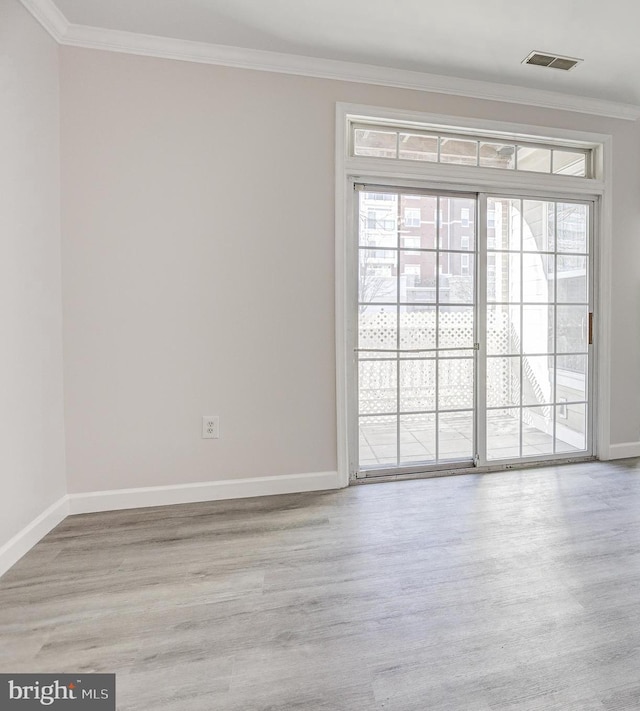 spare room featuring visible vents, a healthy amount of sunlight, crown molding, and wood finished floors