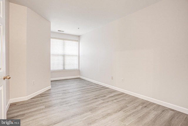 spare room with wood finished floors, visible vents, and baseboards