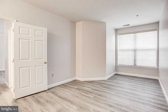 empty room with visible vents, baseboards, and light wood-style floors