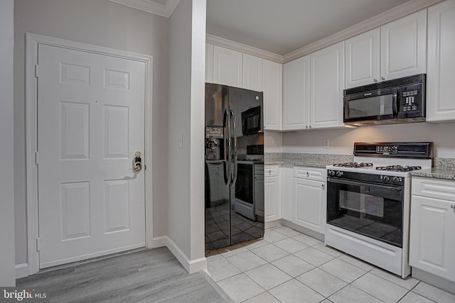 kitchen with light stone countertops, ornamental molding, black appliances, light tile patterned floors, and white cabinets