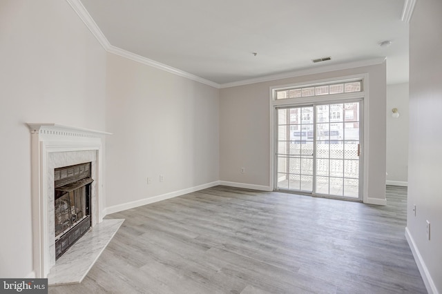 unfurnished living room featuring visible vents, wood finished floors, ornamental molding, and a high end fireplace