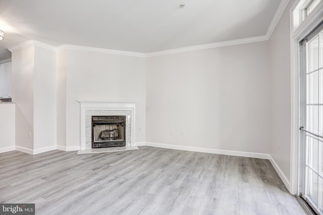 unfurnished living room featuring a high end fireplace, light hardwood / wood-style floors, and crown molding