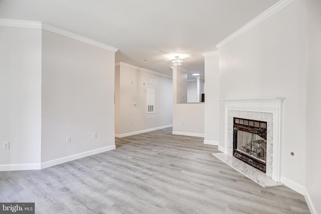 unfurnished living room with a high end fireplace, ornamental molding, baseboards, and wood finished floors