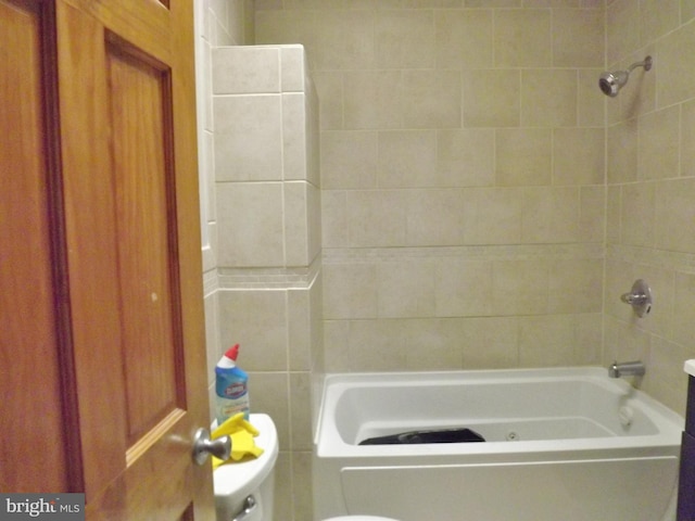 bathroom featuring tiled shower / bath combo and toilet