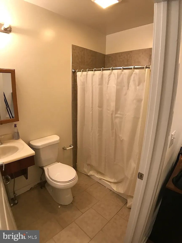 bathroom with tile patterned flooring, toilet, curtained shower, and sink