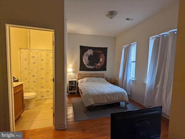 bedroom with light wood-type flooring and connected bathroom