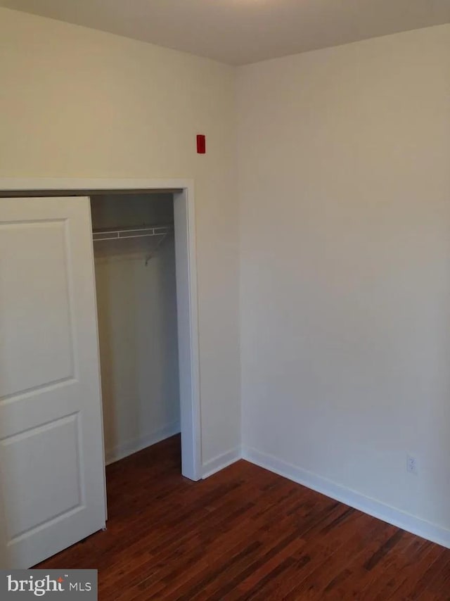 unfurnished bedroom with dark hardwood / wood-style floors and a closet