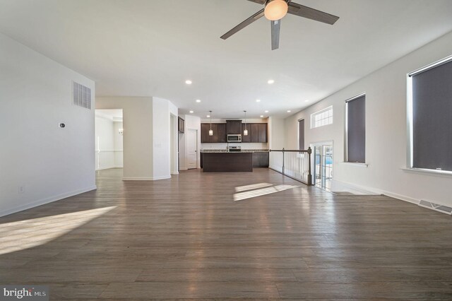 unfurnished living room featuring visible vents, baseboards, and dark wood-style floors