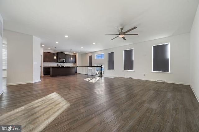 unfurnished living room with dark wood finished floors, visible vents, recessed lighting, and baseboards