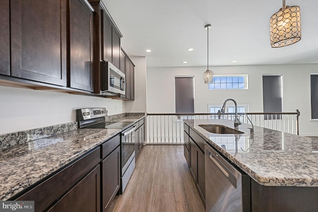 kitchen featuring dark brown cabinetry, light wood-style flooring, stainless steel appliances, and a sink