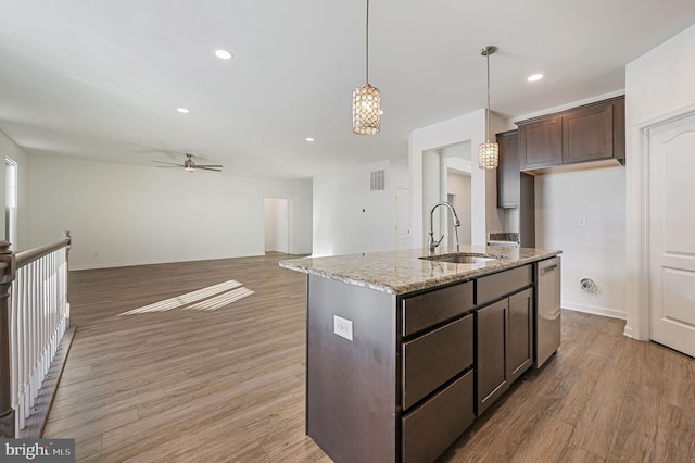 kitchen featuring dark brown cabinets, light stone countertops, dishwasher, light wood-type flooring, and a sink