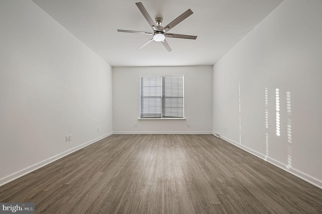 empty room featuring dark wood-type flooring, baseboards, and ceiling fan