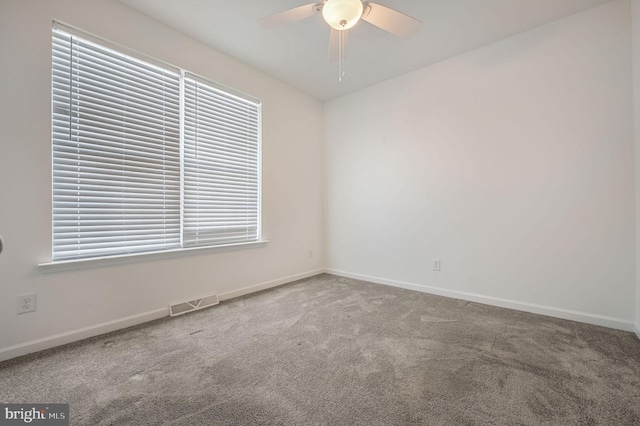 carpeted empty room featuring a ceiling fan, visible vents, and baseboards