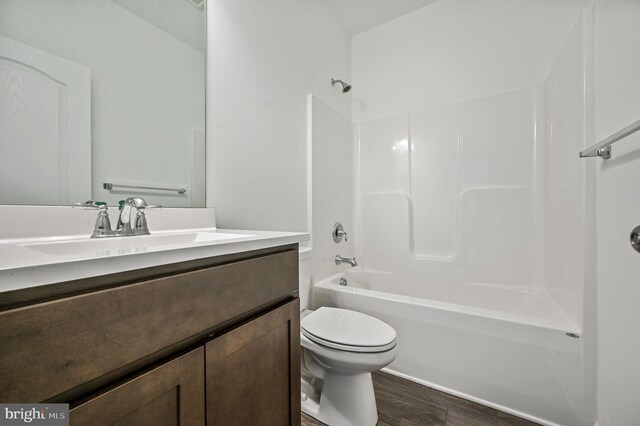 full bath featuring toilet, vanity,  shower combination, and wood finished floors