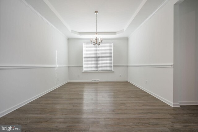 unfurnished dining area featuring visible vents, baseboards, wood finished floors, a notable chandelier, and a raised ceiling