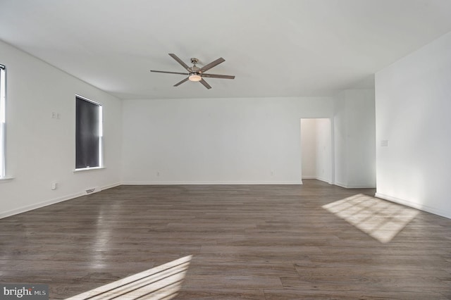 spare room with visible vents, baseboards, dark wood-type flooring, and ceiling fan