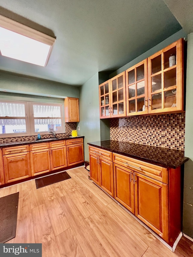 kitchen with dark stone countertops, light wood-type flooring, and tasteful backsplash